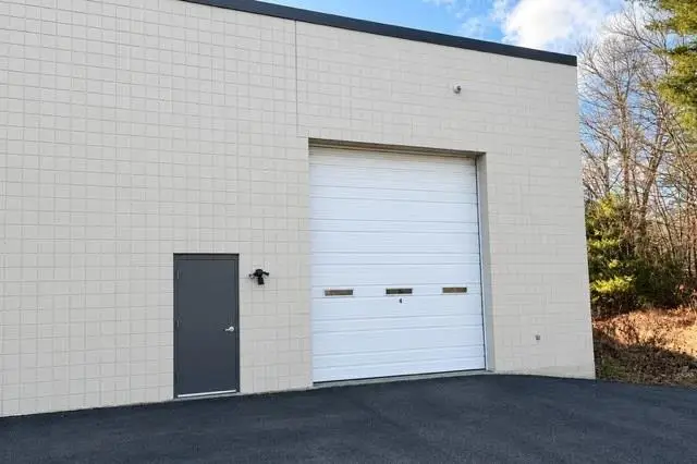 Large white drive-in overhead door next to a steel entry door